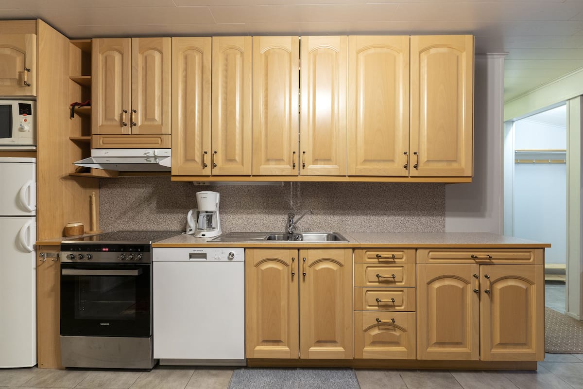 A kitchen with wooden cabinets, a microwave, a stove, a dishwasher, and a coffee maker.