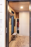 Um interior de madeira com um banco, um cabideiro e um guarda-roupa.