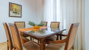 Un comedor con una mesa de vidrio, sillas de madera y un tazón amarillo con piñas.