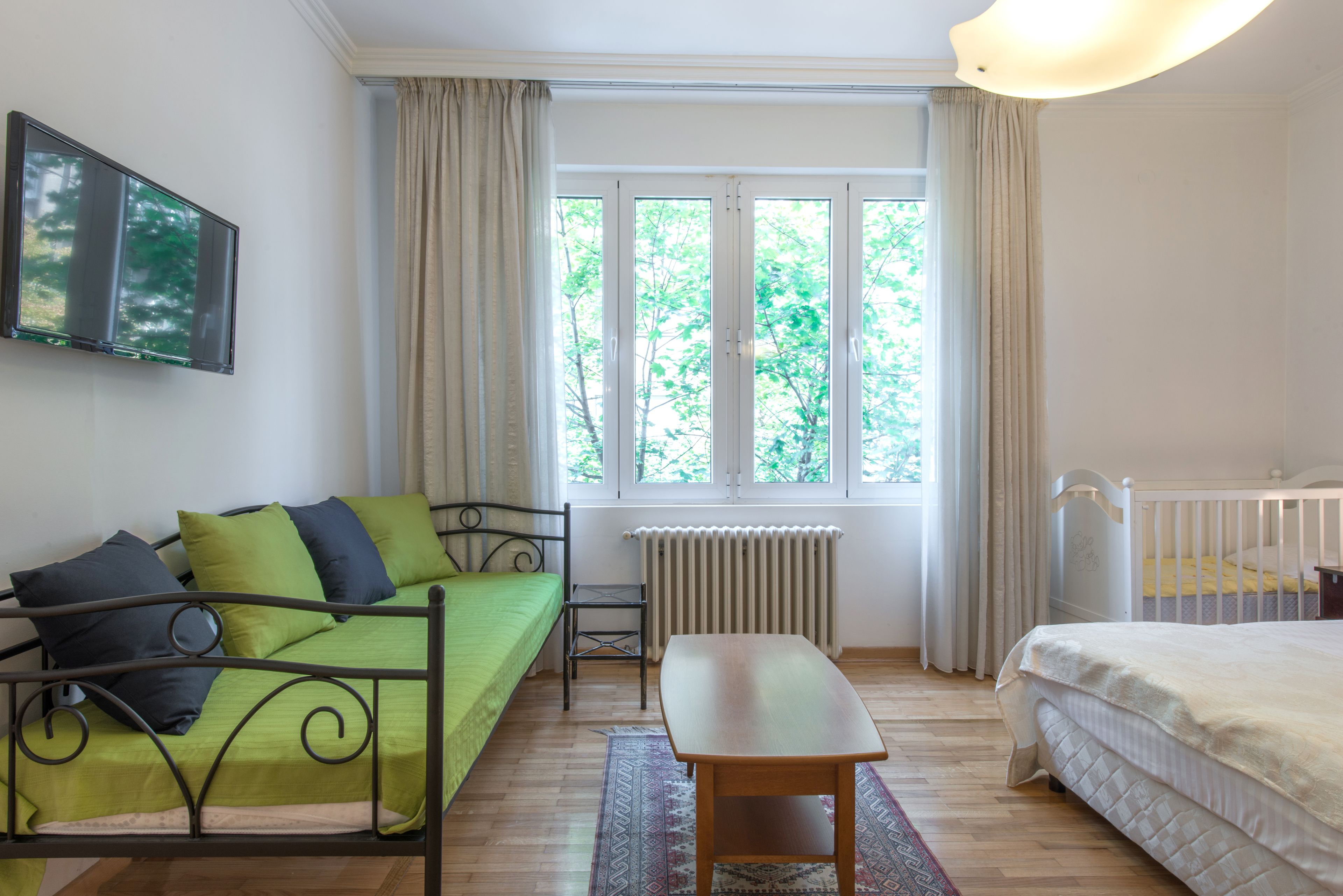 A room with a bed, a sofa, a table, and a window with curtains.