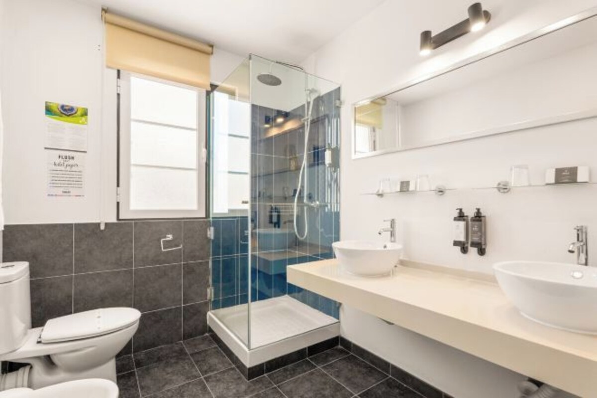 A modern bathroom with a glass-enclosed shower, a white sink, and a toilet.