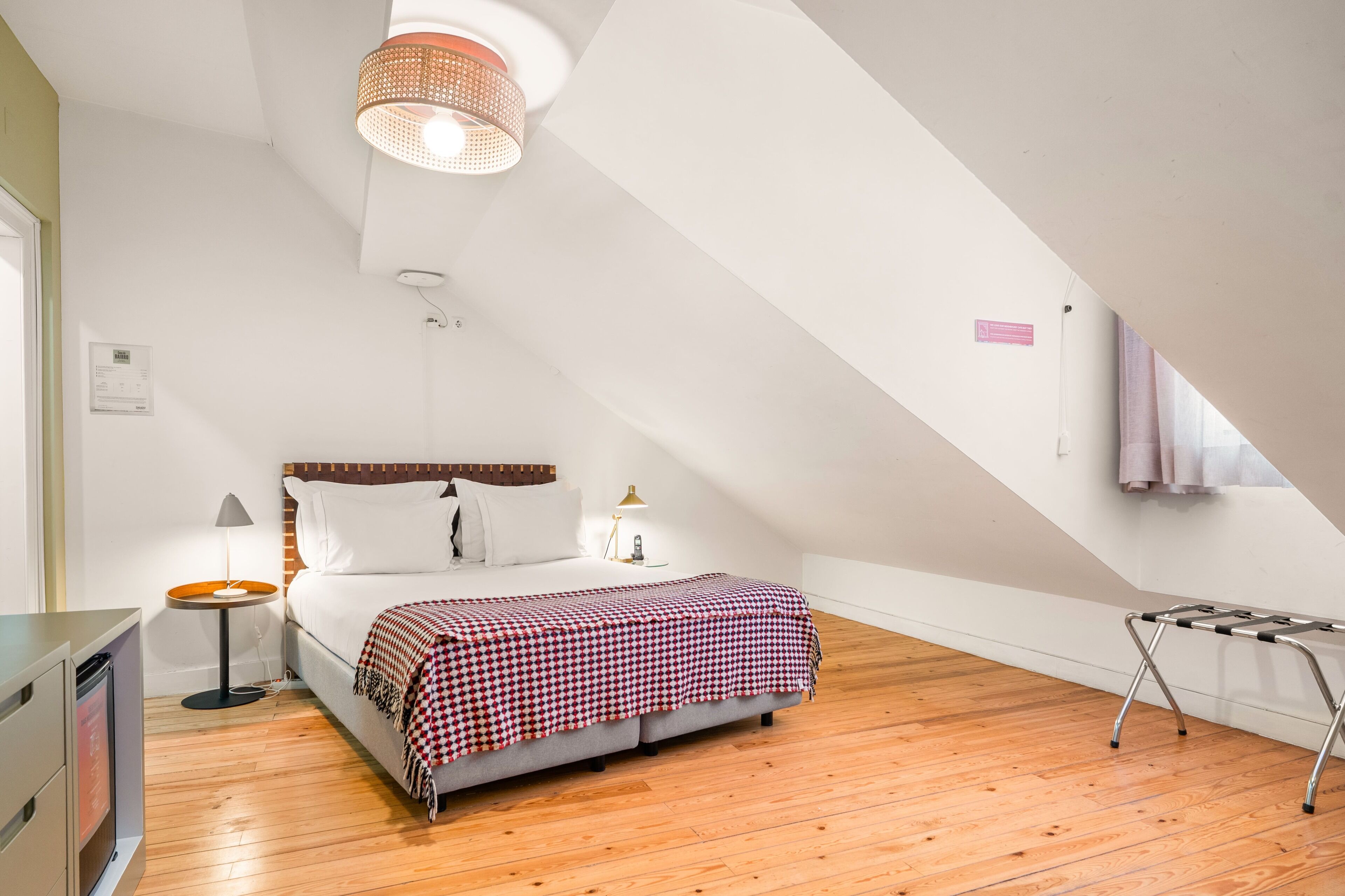 A bedroom with a bed, bedside table, lamp, and a hanging light fixture.