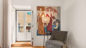 A room with a grey armchair, a floor lamp, and a painting on the wall. - Casa do Bairro by Shiadu (Lisbon)