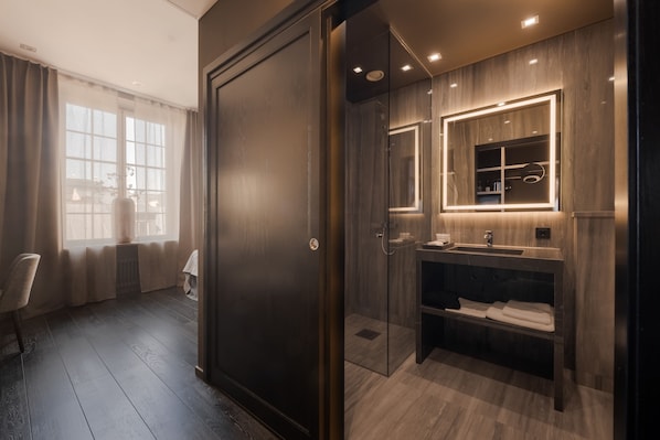 A modern bathroom with a glass shower enclosure, a vanity with a mirror, and a towel rack.