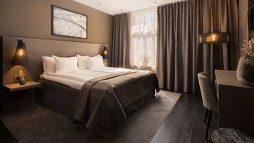 A modern hotel room with a large bed, a desk, and a chair.