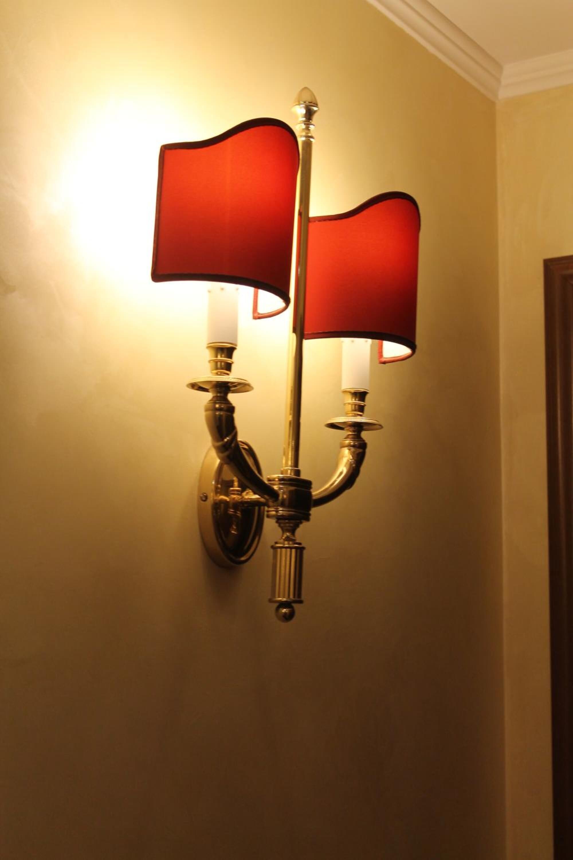 Een wandlamp met twee rode kapjes en een witte kap.