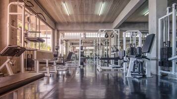 Un gimnasio con diversos equipos de ejercicio, que incluyen máquinas de pesas y pesas sueltas.