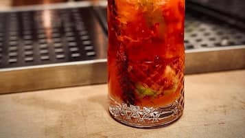Ein Cocktailglas mit einem roten Getränk, verziert mit Beeren und einem Strohhalm, auf einer Bar.