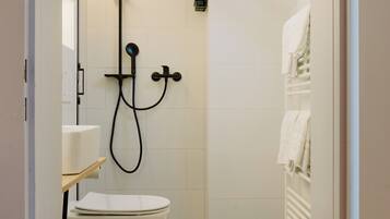 A modern bathroom with a toilet, a shower, and a towel rack.