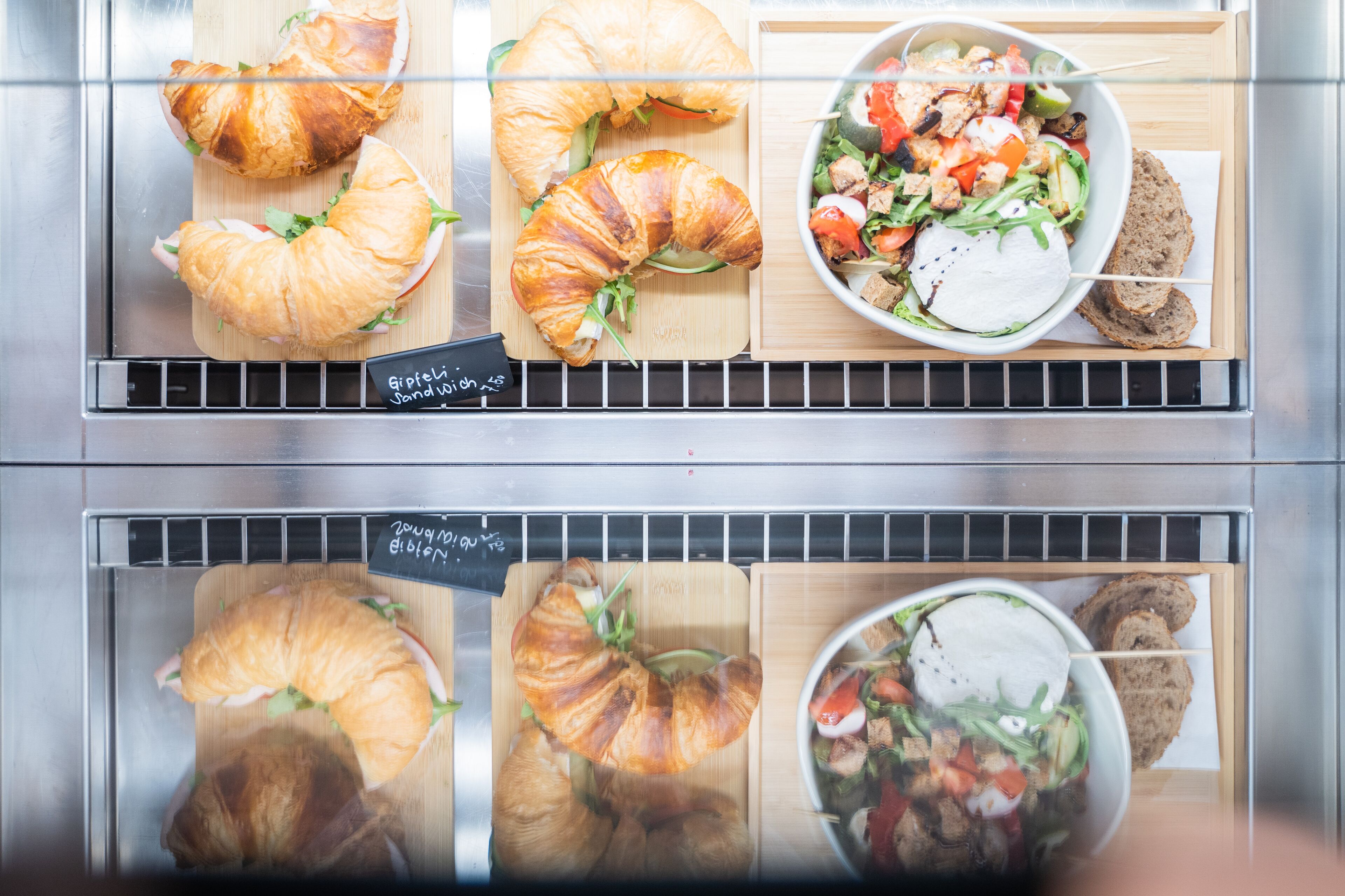 A bakery display with croissants and a salad bowl.