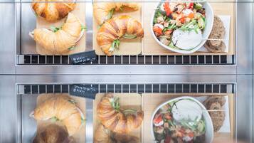 A bakery display with croissants and a salad bowl.