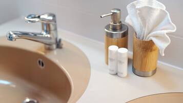 A bathroom sink with a modern faucet, a soap dispenser, and a container holding a white towel.