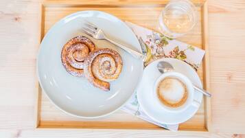 Ett bricka med en tallrik kanelbullar och en kopp kaffe på ett träbord.