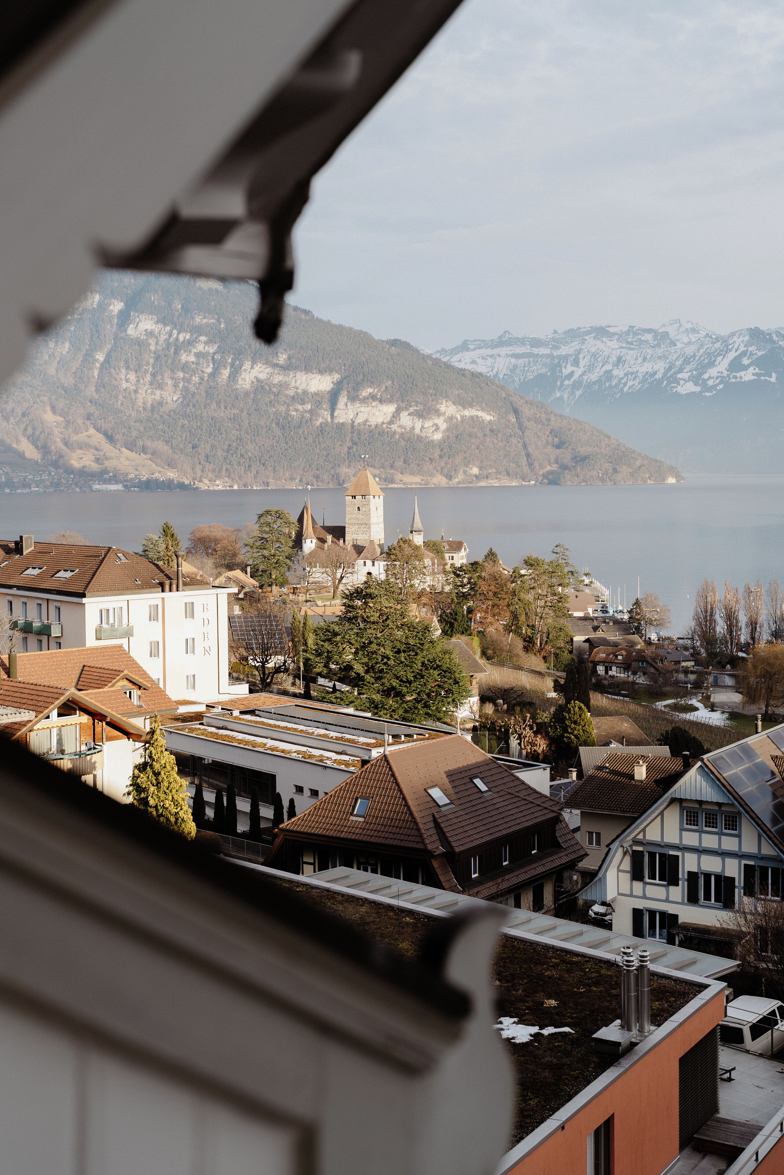 A view of a town with buildings, a church, and mountains in the background.