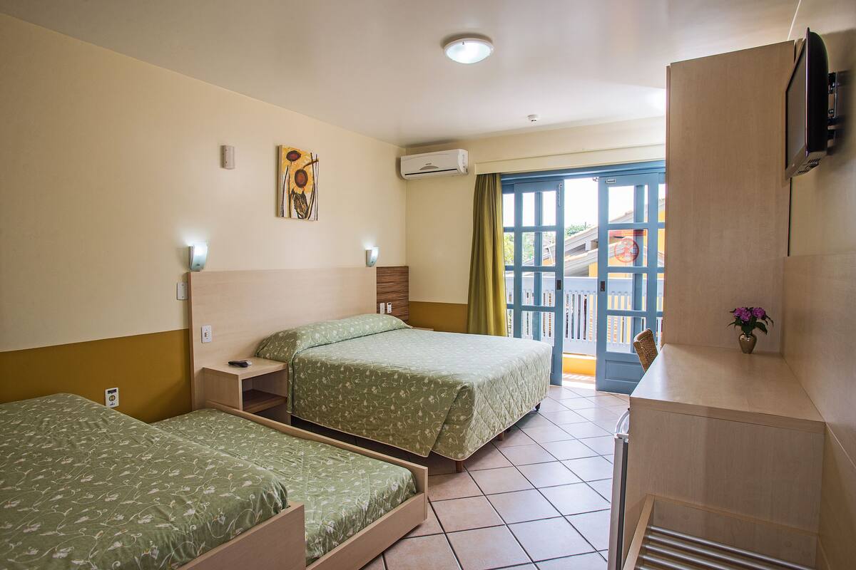 Hotellihuone, jossa on kaksi sänkyä, työpöytä, tuoli, televisio ja ovi, joka johtaa ulos.