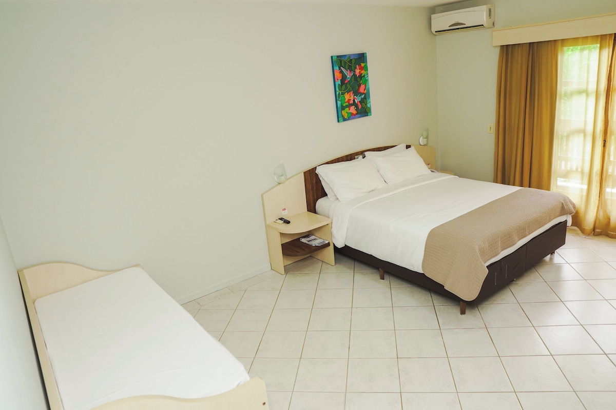 Una habitación de hotel con cama, mesita de noche y un escritorio pequeño.