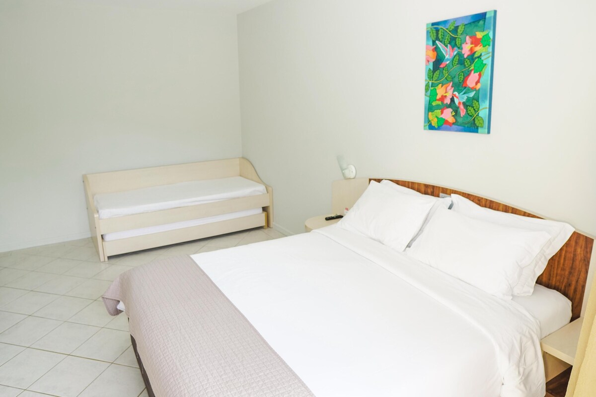 A bedroom with a bed, a nightstand, and a small bench.