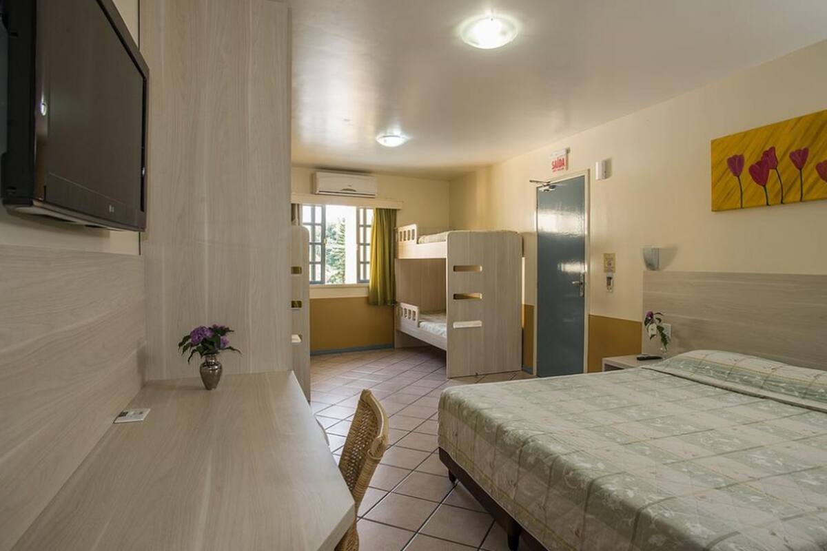 Hotellihuone, jossa on sänky, työpöytä, tuoli, televisio, vaatekaappi ja taulu seinällä.