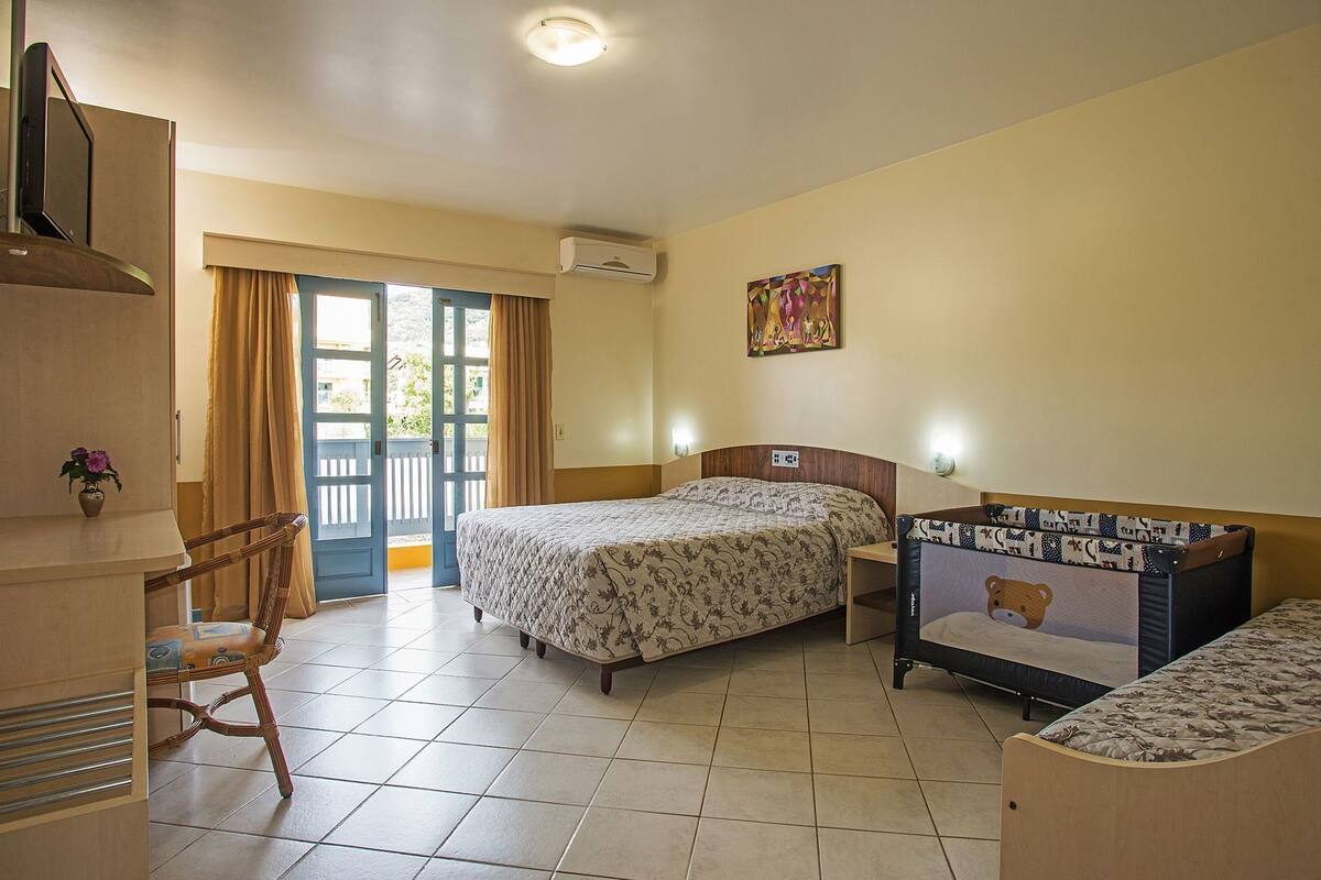Hotellihuone, jossa on kaksi sänkyä, tuoli, työpöytä ja ikkuna, jossa on verhot.