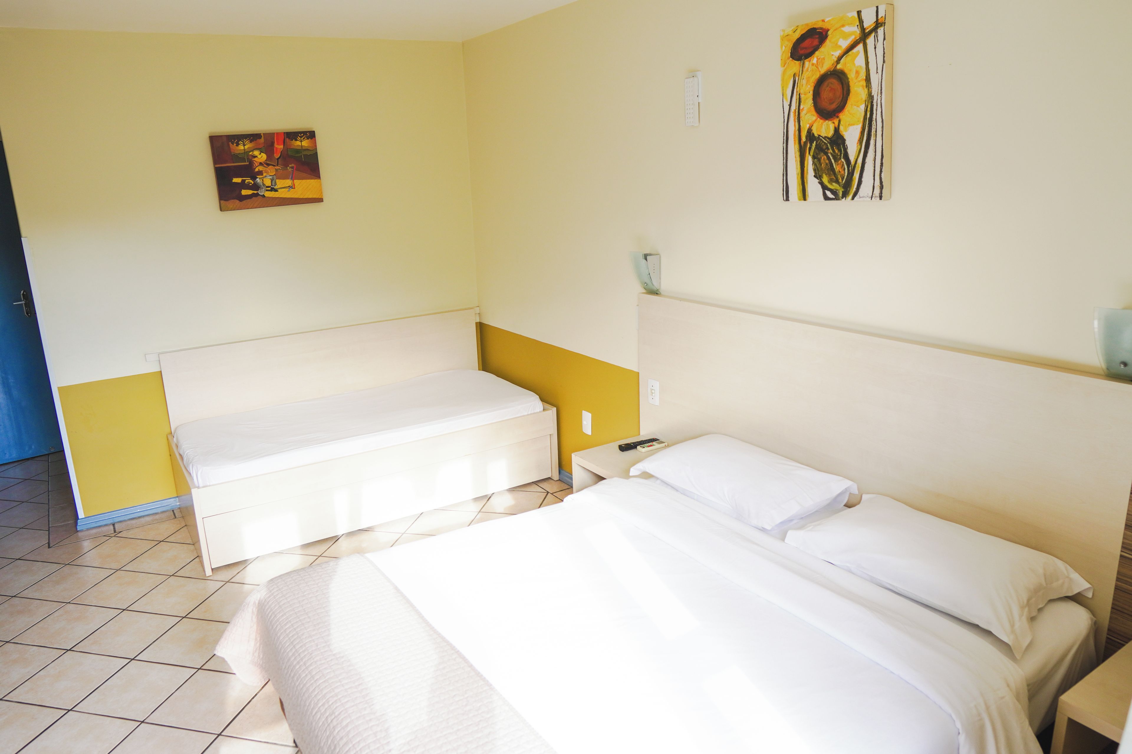 A hotel room with a bed, a sofa, and a painting on the wall.