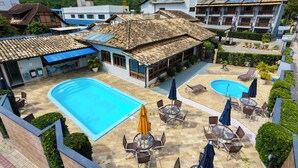 A hotel with a swimming pool, outdoor seating, and a mountain backdrop. - Vila Olaria Hotel (Penha)