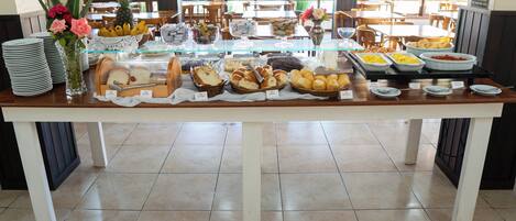 Una mesa de buffet con diversas opciones de comida y un jarrón de flores.