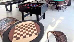 A spacious indoor area with a foosball table, a pool table, and a checkered table. - Vila Olaria Hotel (Penha)