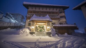Un hotel con una entrada cubierta de nieve y escalones que conducen a la puerta.