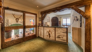 Un vestíbulo con un mostrador de recepción de madera, un mural con motivos de esquí y una exposición de cabeza de ciervo.