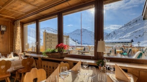 Un restaurante acogedor con interiores de madera, amplias ventanas que ofrecen vistas a la montaña y una mesa lista para comer.