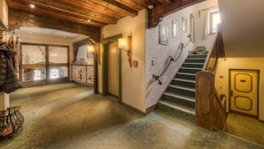 Una escalera de madera con barandilla, un aplique de pared y una puerta con marco verde.