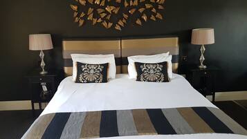 Un lit double avec une couvre-lit à rayures, deux coussins décoratifs, un tableau mural et deux lampes de chevet.