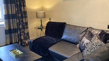 A modern living room with a sectional sofa, a coffee table, and a lamp.