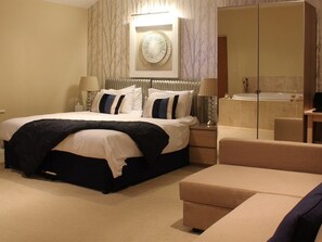 A hotel room with a bed, bedside table, lamp, and a bathroom with a bathtub.