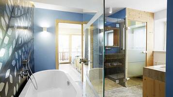 Un baño moderno con una bañera grande, cabina de ducha de vidrio y un mueble de tocador de madera.