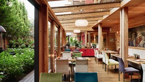 A restaurant with wooden beams, large windows, and a garden view. - DasPosthotel – Boutique Hotel (Zell am Ziller)