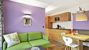Una sala moderna con un sofá verde, una mesa de comedor de madera y una cocina al fondo.