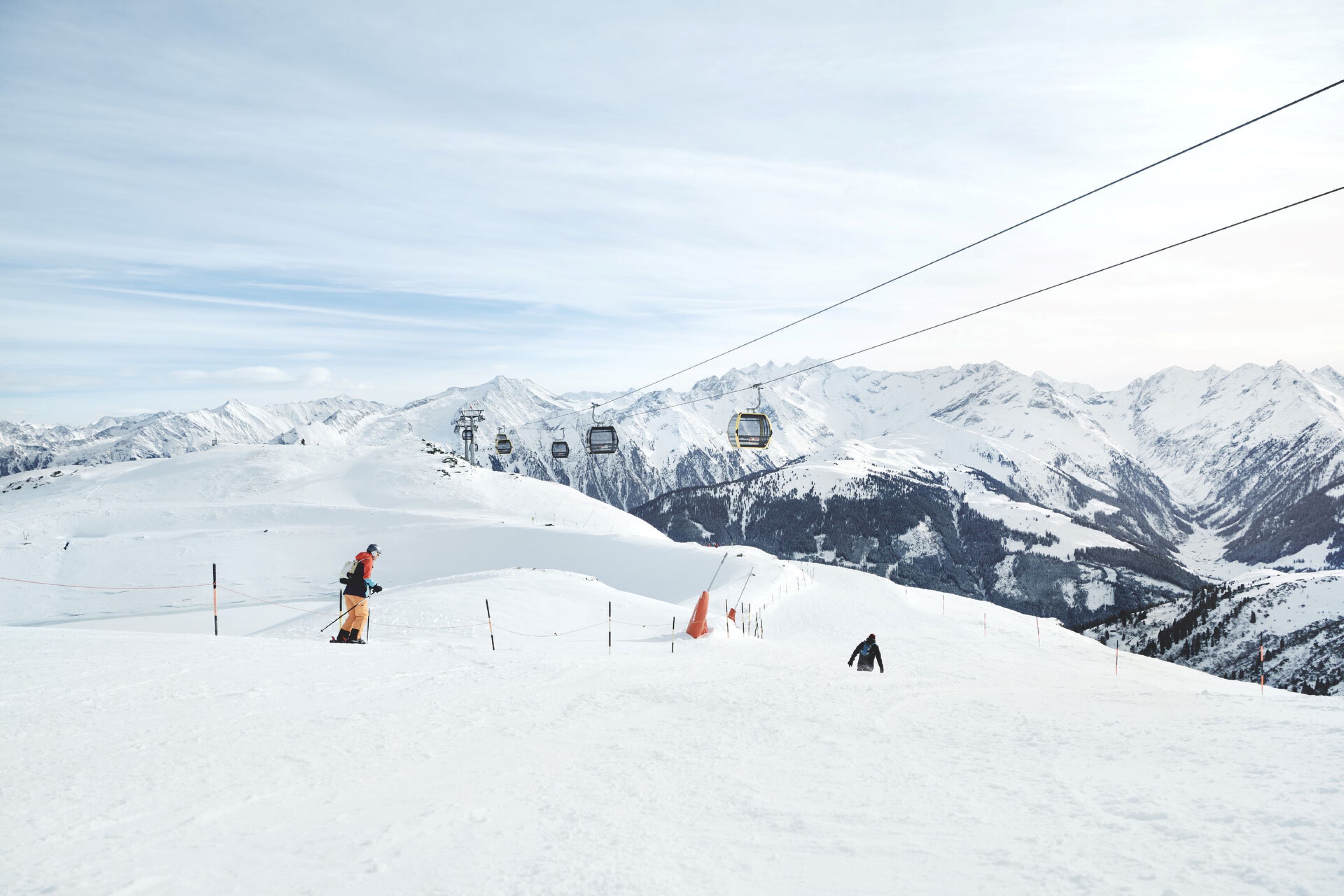Eine Skipiste mit Sessellift, schneebedeckten Bergen und Skifahrern.