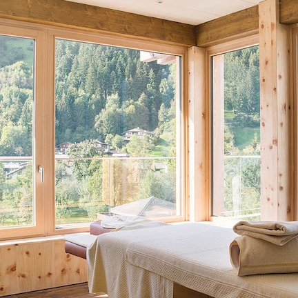 A room with large windows offering a view of a forested hillside.