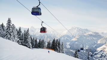 A ski lift with cabins moving up a snowy mountain slope.