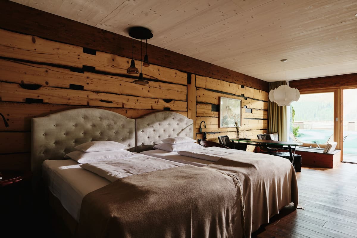 Une chambre avec un grand lit, des murs en bois et une vue sur l’extérieur.