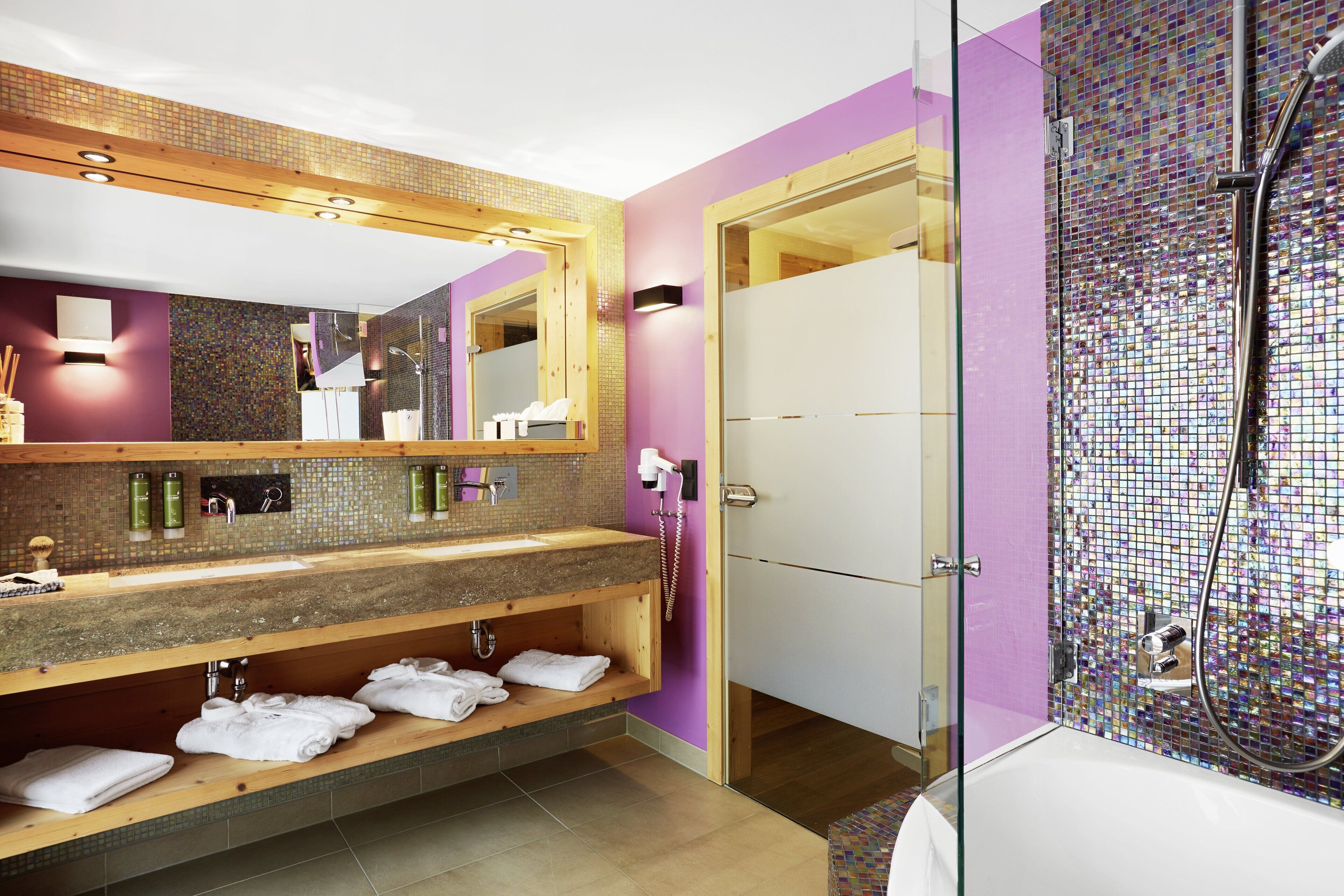 A modern bathroom with a wooden vanity, a large mirror, and a glass shower enclosure.