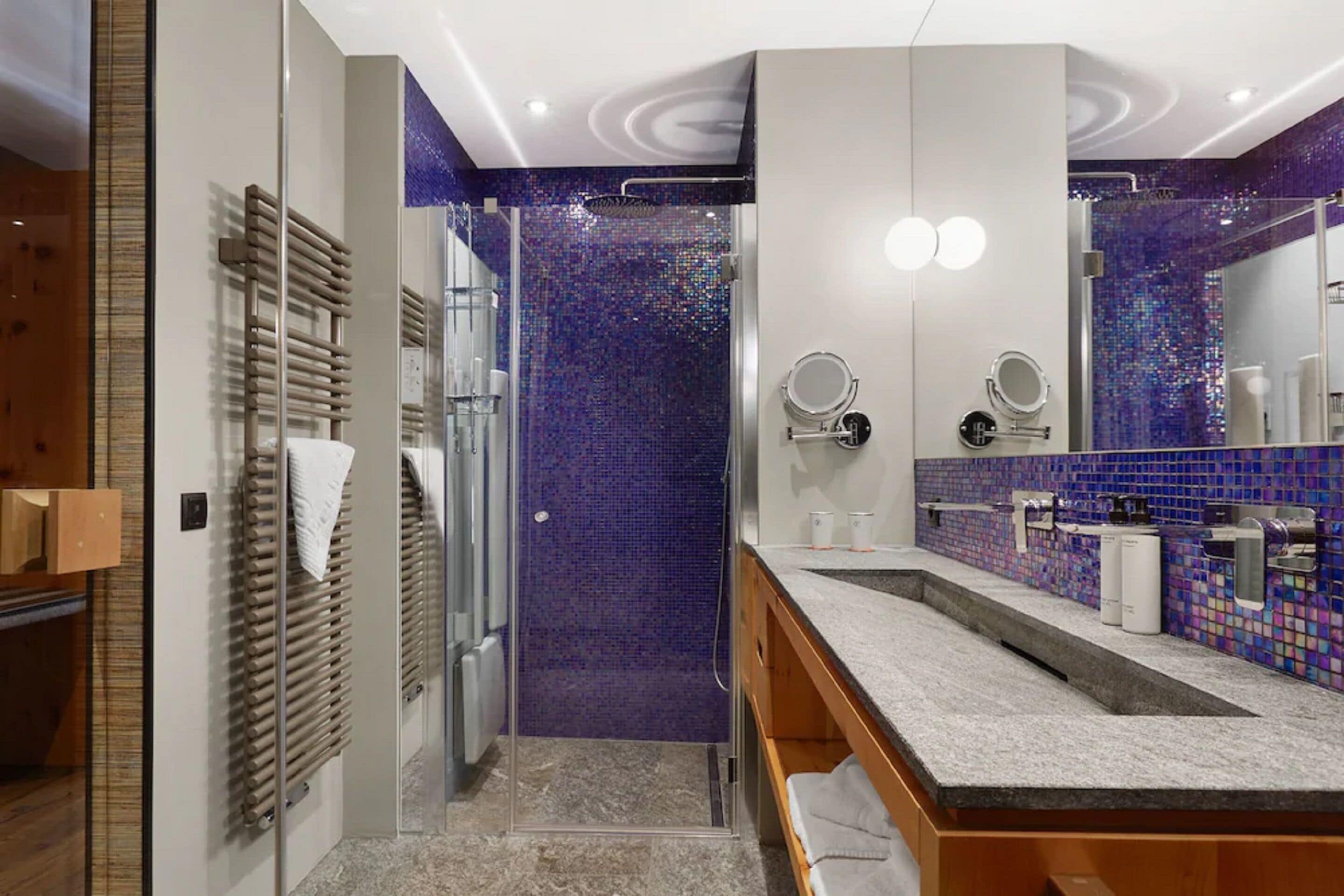 A modern bathroom with a shower, two sinks, and a large mirror.