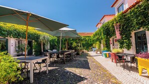 An outdoor café with tables and chairs, surrounded by greenery and cobblestone paths. - Casa do Patio by Shiadu (Lisbon)