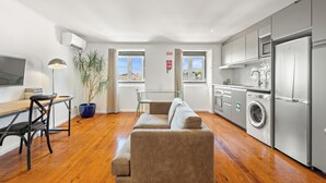 A modern kitchen with a sofa, washing machine, and dining area. - Casa do Patio by Shiadu (Lisbon)