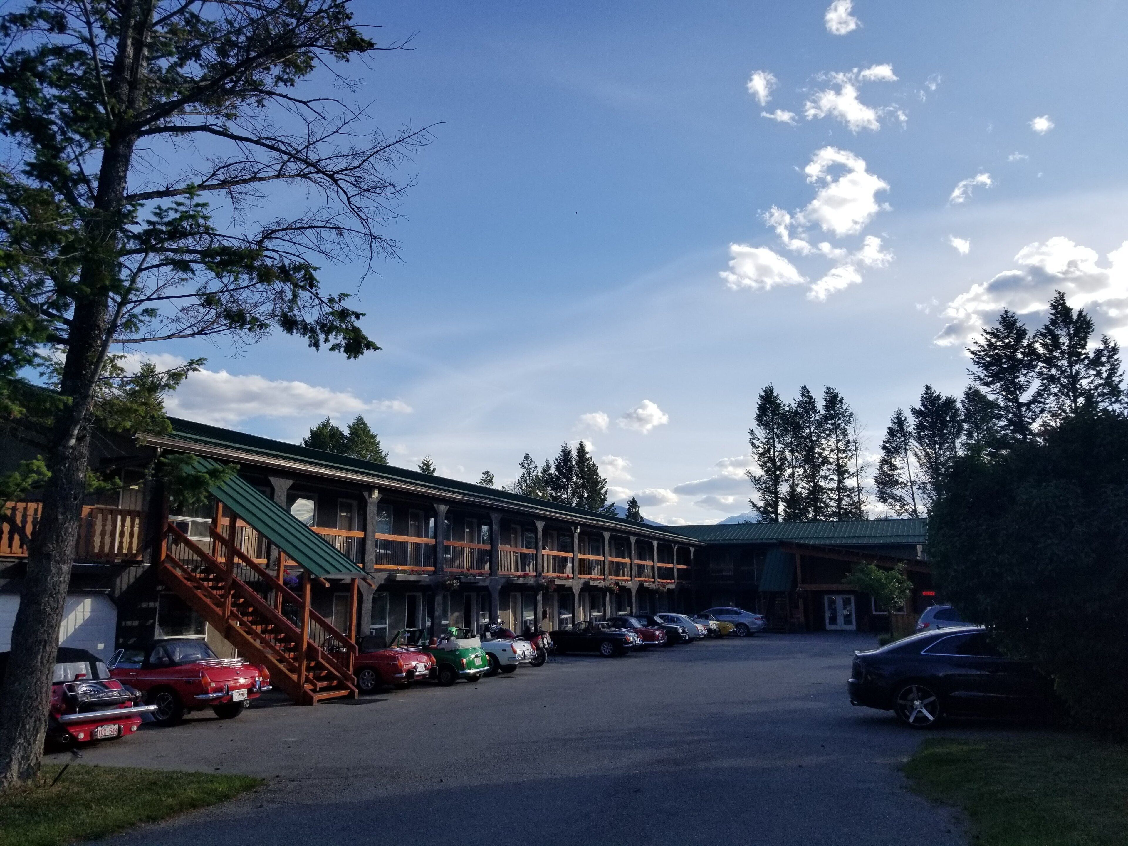 Un chalet comprenant une série de chambres, un espace de stationnement couvert et un paysage montagneux en toile de fond.