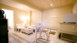 A compact kitchen with a granite countertop, a built-in sink, and a white refrigerator. - Crystal Springs Lodge (Radium Hot Springs)