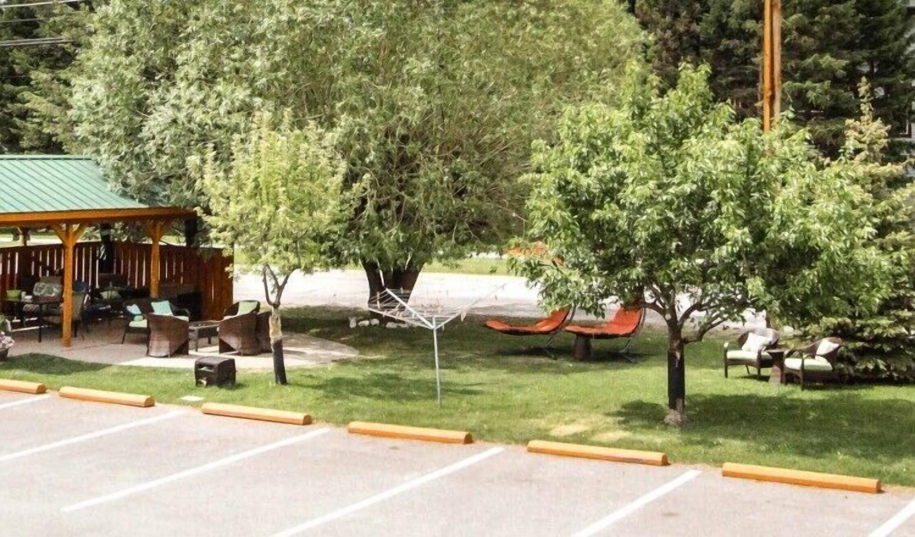 Un espacio al aire libre con mesas y sillas, césped y árboles.