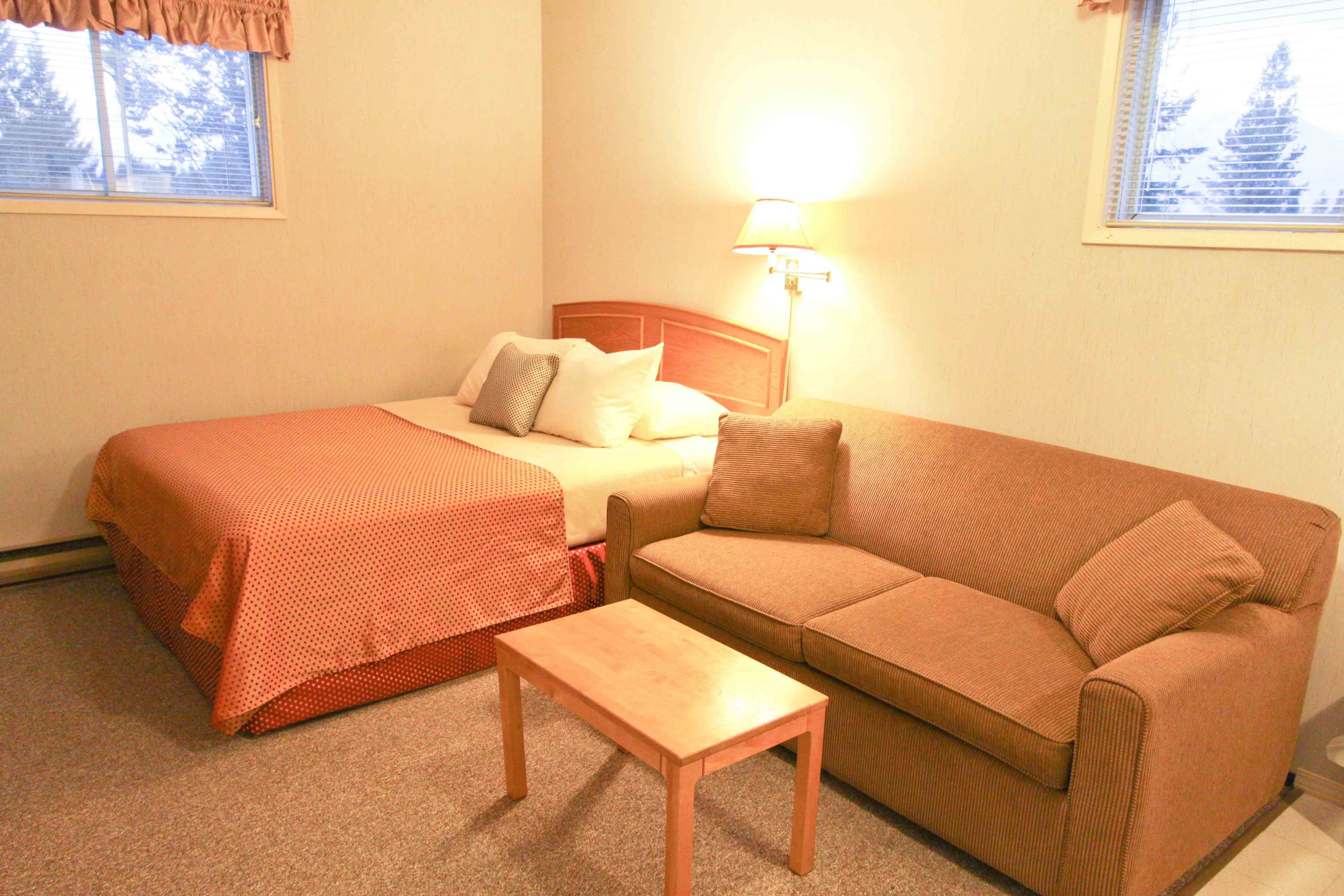 Ein Hotelzimmer mit einem Bett, einer Couch, einem kleinen Tisch und einer Lampe.