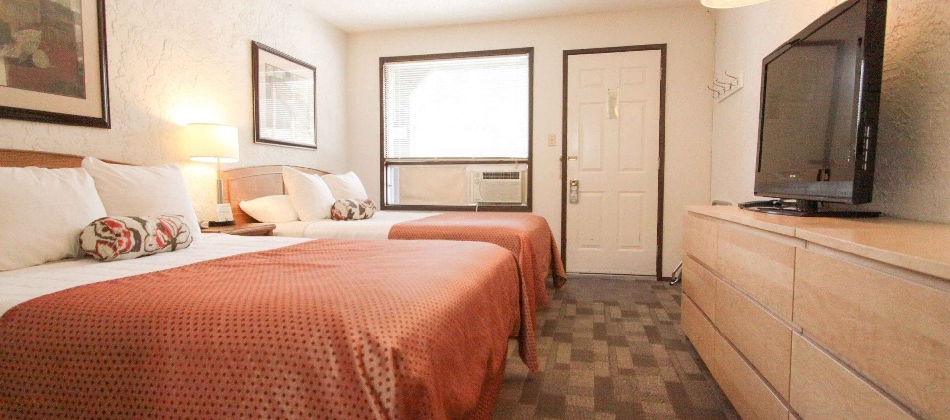 Habitación de hotel con dos camas, televisión, escritorio y ventana.